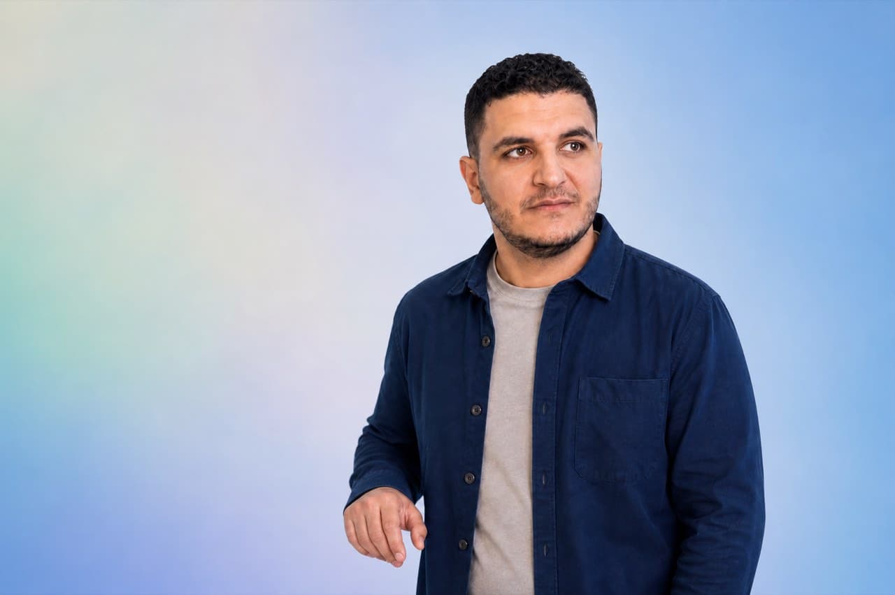Ahmed Awad against a soft blue, mint and ivory studio background